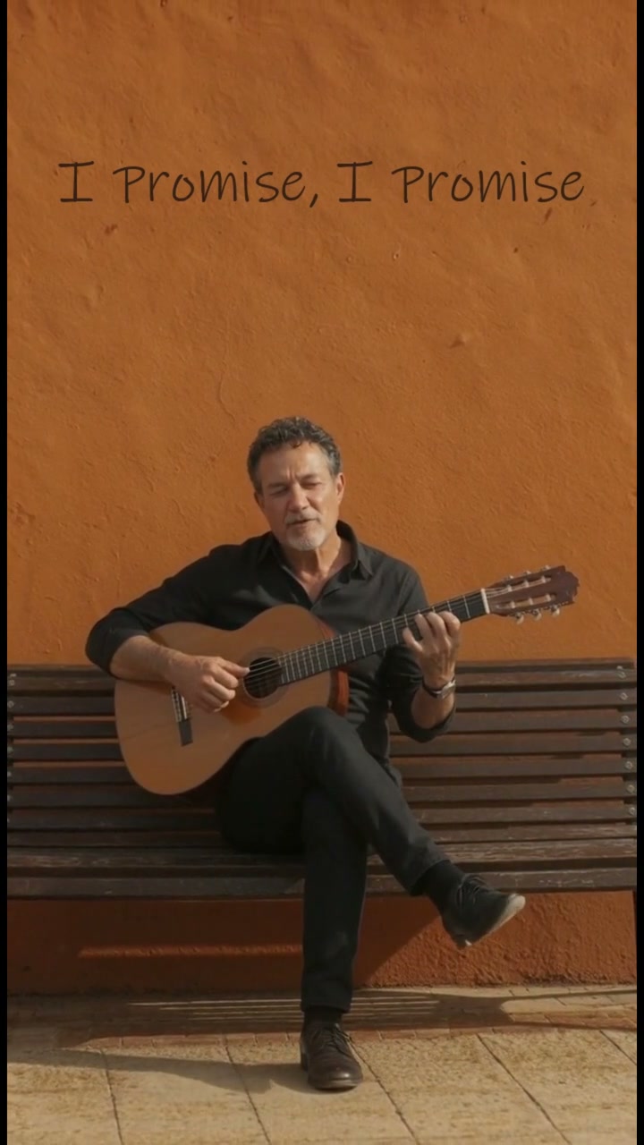 Will Wehi seated with a guitar against an orange wall in I Promise, I Promise